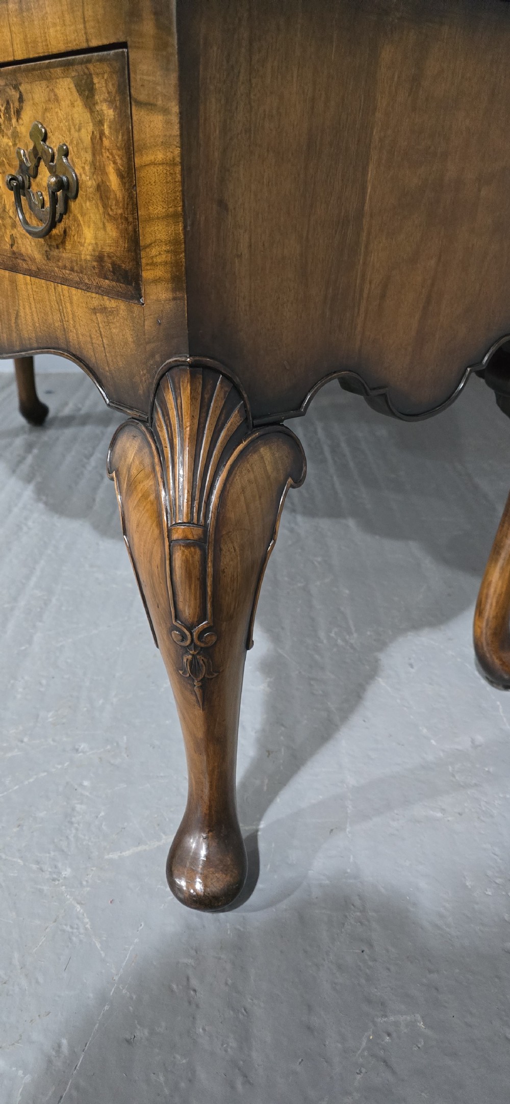 A double-door glazed burr walnut bookcase on stand featuring an arched pediment, astragal glazing bars, three lower drawers, and cabriole legs. View IX