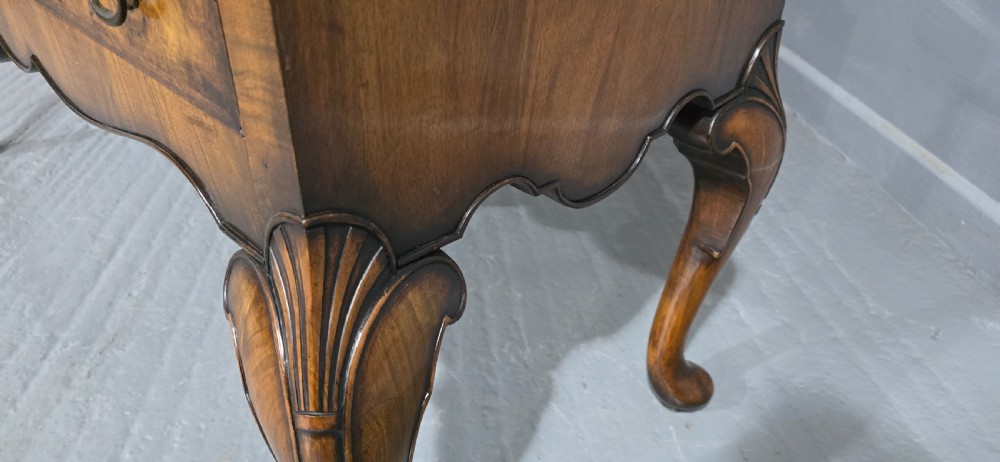 A double-door glazed burr walnut bookcase on stand featuring an arched pediment, astragal glazing bars, three lower drawers, and cabriole legs. View XI