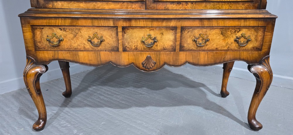 A double-door glazed burr walnut bookcase on stand featuring an arched pediment, astragal glazing bars, three lower drawers, and cabriole legs. View XV