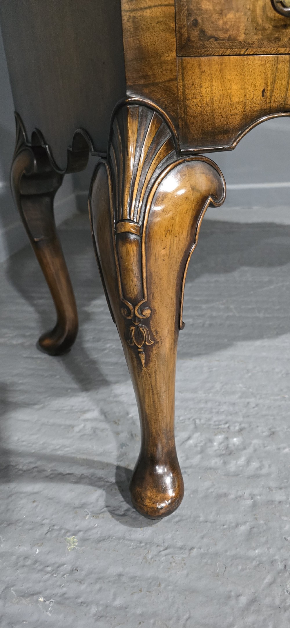 A double-door glazed burr walnut bookcase on stand featuring an arched pediment, astragal glazing bars, three lower drawers, and cabriole legs. View XXII