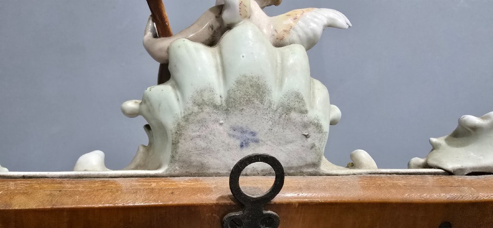 An antique Dresden porcelain easel mirror decorated with sculpted cherubs, encrusted pastel flowers, and Rococo scrollwork around a rectangular glass frame. View IX