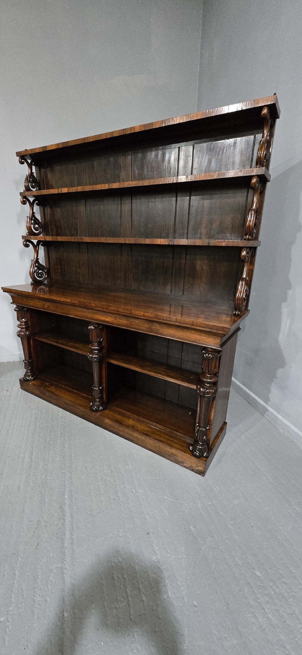 A large 19th-century William IV open mahogany waterfall bookcase with tiered graduated shelves filled with books and carved pilasters. View III