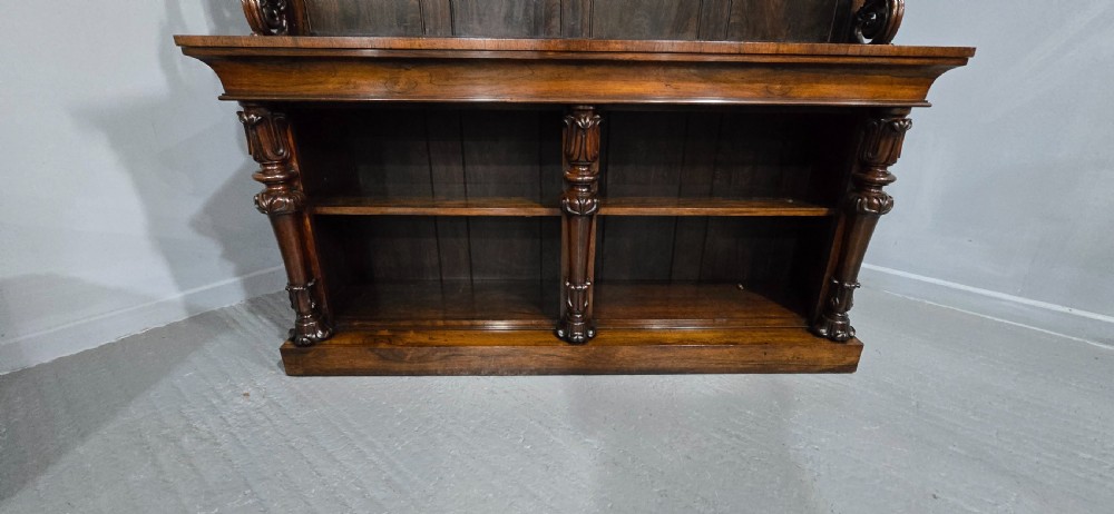A large 19th-century William IV open mahogany waterfall bookcase with tiered graduated shelves filled with books and carved pilasters. View VIII