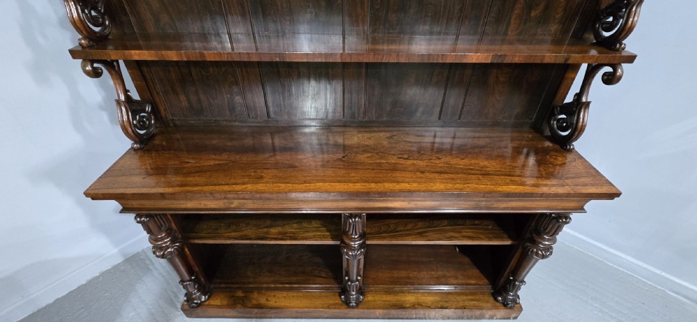 A large 19th-century William IV open mahogany waterfall bookcase with tiered graduated shelves filled with books and carved pilasters. View XI