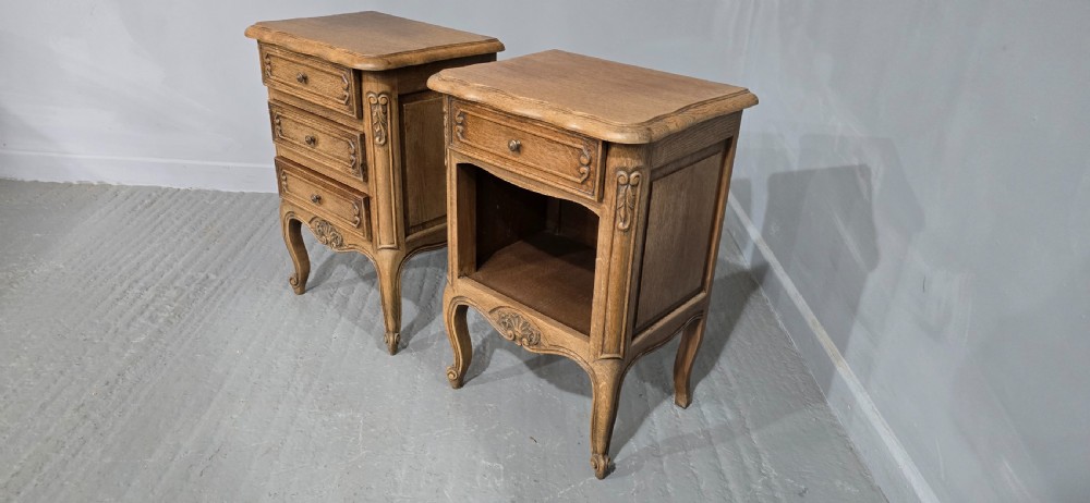 A pair of French bleached oak bedside cabinets featuring cabriole legs, carved aprons, and moulded drawer fronts, with one unit containing three drawers and the other featuring a single drawer above an open shelf. View V