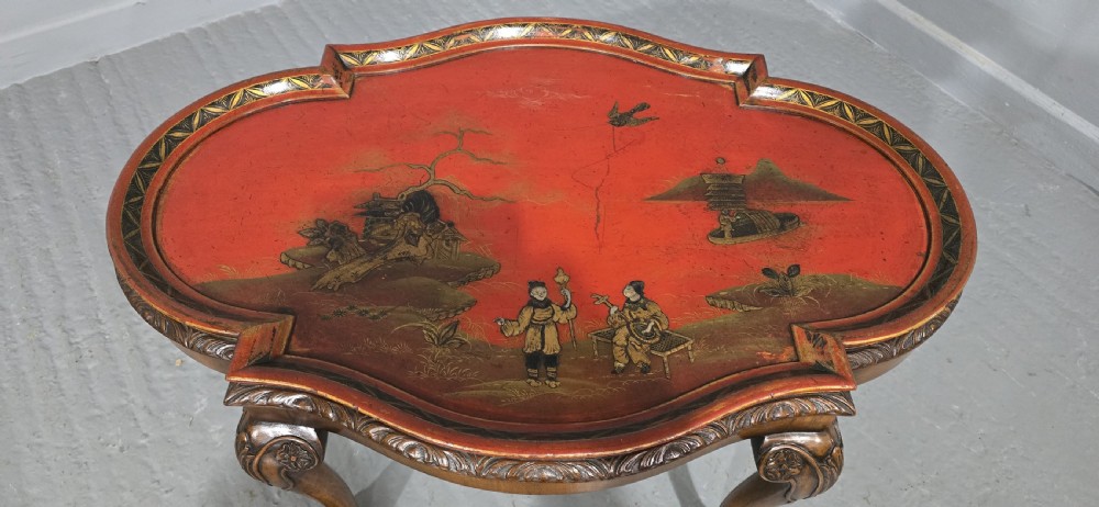 A low shaped coffee table featuring a red lacquered Chinoiserie top with painted figures and a carved walnut base with cabriole legs. View III