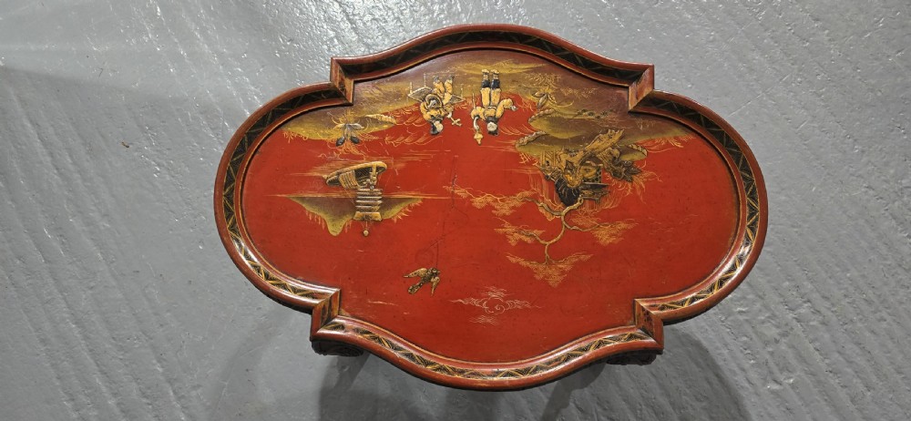 A low shaped coffee table featuring a red lacquered Chinoiserie top with painted figures and a carved walnut base with cabriole legs. View V