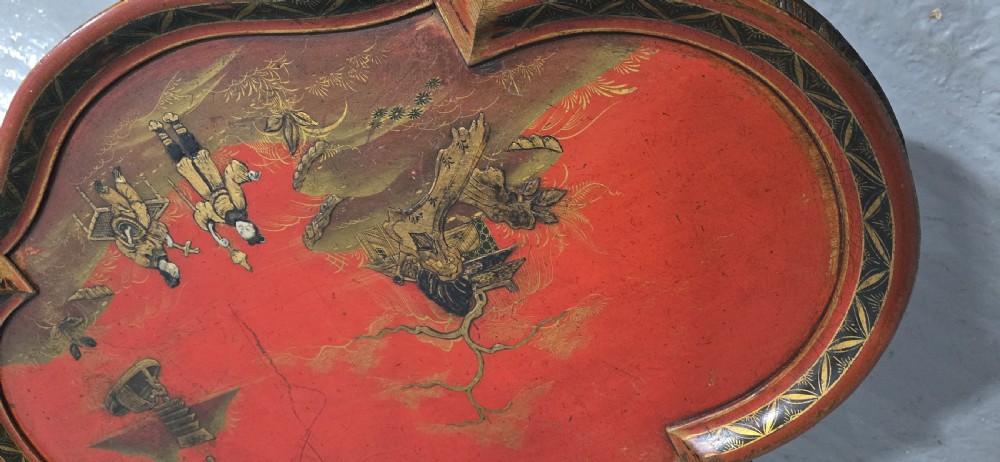 A low shaped coffee table featuring a red lacquered Chinoiserie top with painted figures and a carved walnut base with cabriole legs. View VI