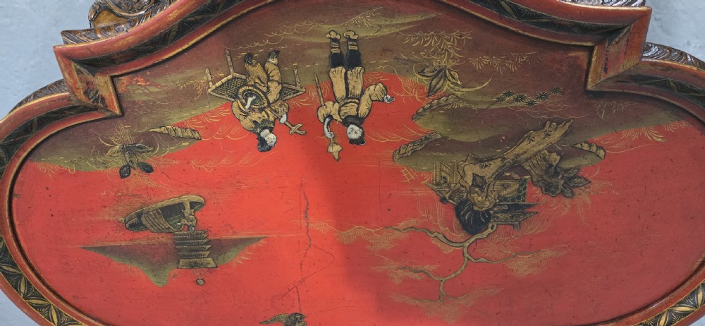 A low shaped coffee table featuring a red lacquered Chinoiserie top with painted figures and a carved walnut base with cabriole legs. View VII
