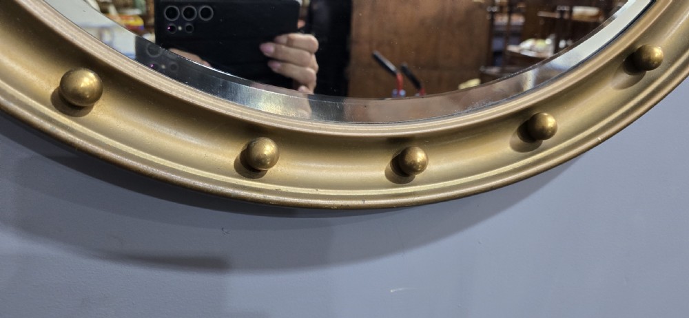 An oval Victorian gilt wall mirror featuring a molded gold frame accented with spherule ball details around the perimeter. View II