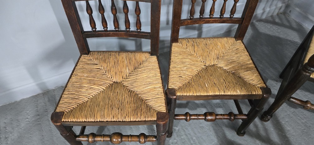 A set of six dark brown 19th-century country dining chairs featuring spindle backrests and woven rush seats. View IV