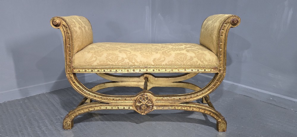 A French Neoclassical giltwood window seat featuring scrolled armrests, carved beaded frame details, and gold damask upholstery. View III