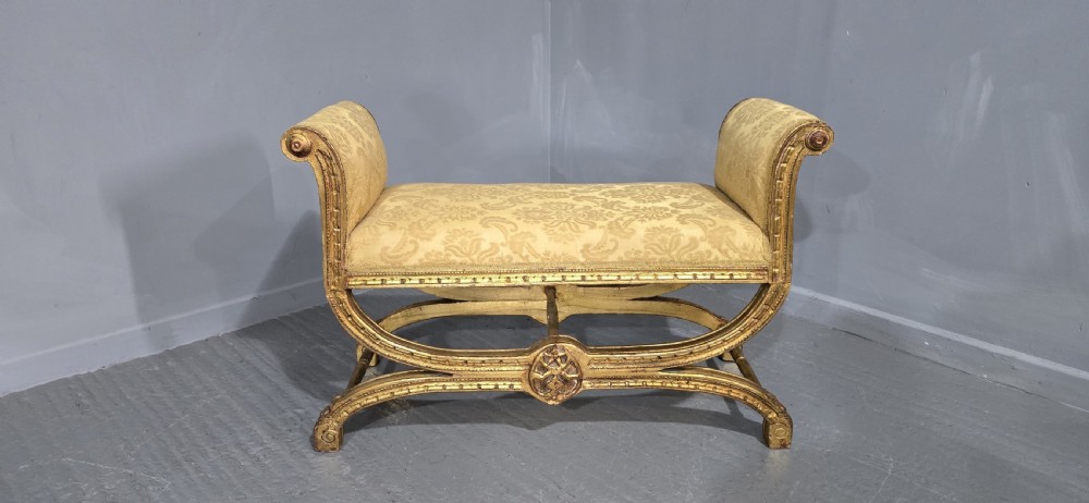 A French Neoclassical giltwood window seat featuring scrolled armrests, carved beaded frame details, and gold damask upholstery. View VII