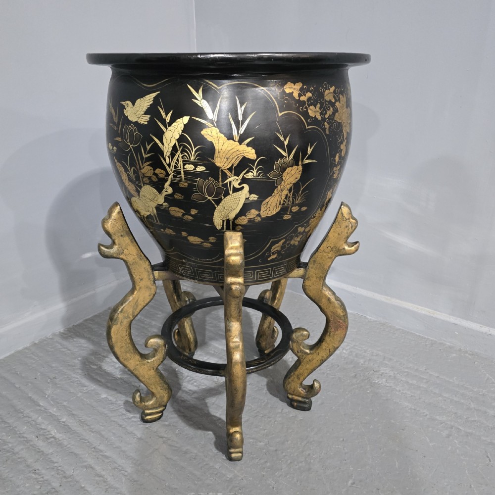 A large black lacquered oriental jardiniere decorated with gold floral and bird imagery, resting upon a carved gold giltwood dragon-form stand. View II