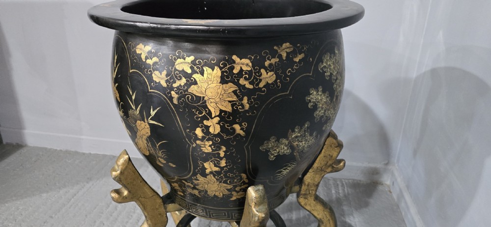 A large black lacquered oriental jardiniere decorated with gold floral and bird imagery, resting upon a carved gold giltwood dragon-form stand. View IV