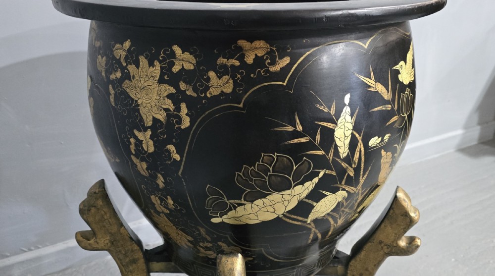 A large black lacquered oriental jardiniere decorated with gold floral and bird imagery, resting upon a carved gold giltwood dragon-form stand. View V
