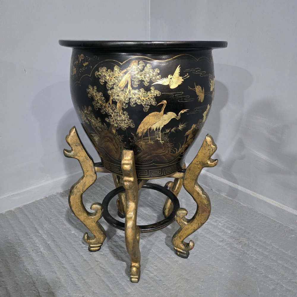 A large black lacquered oriental jardiniere decorated with gold floral and bird imagery, resting upon a carved gold giltwood dragon-form stand. View VI