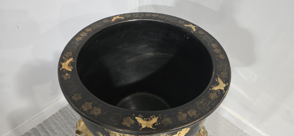 A large black lacquered oriental jardiniere decorated with gold floral and bird imagery, resting upon a carved gold giltwood dragon-form stand. View VII