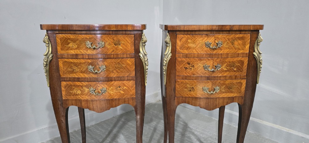A pair of French Louis XV style bedside tables featuring floral marquetry wood veneers, three drawers, gilt brass mounts, and slender cabriole legs. View VI