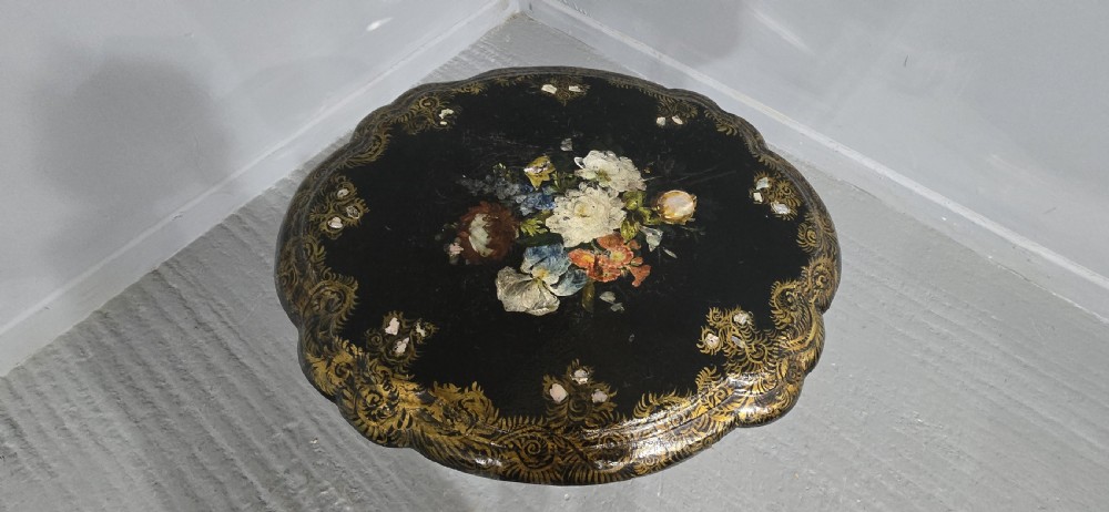 A Victorian black lacquered papier-mache occasional table featuring a scalloped rim, hand-painted floral display, mother-of-pearl inlay, gilded scrolling borders, turned column, and shaped base. View III