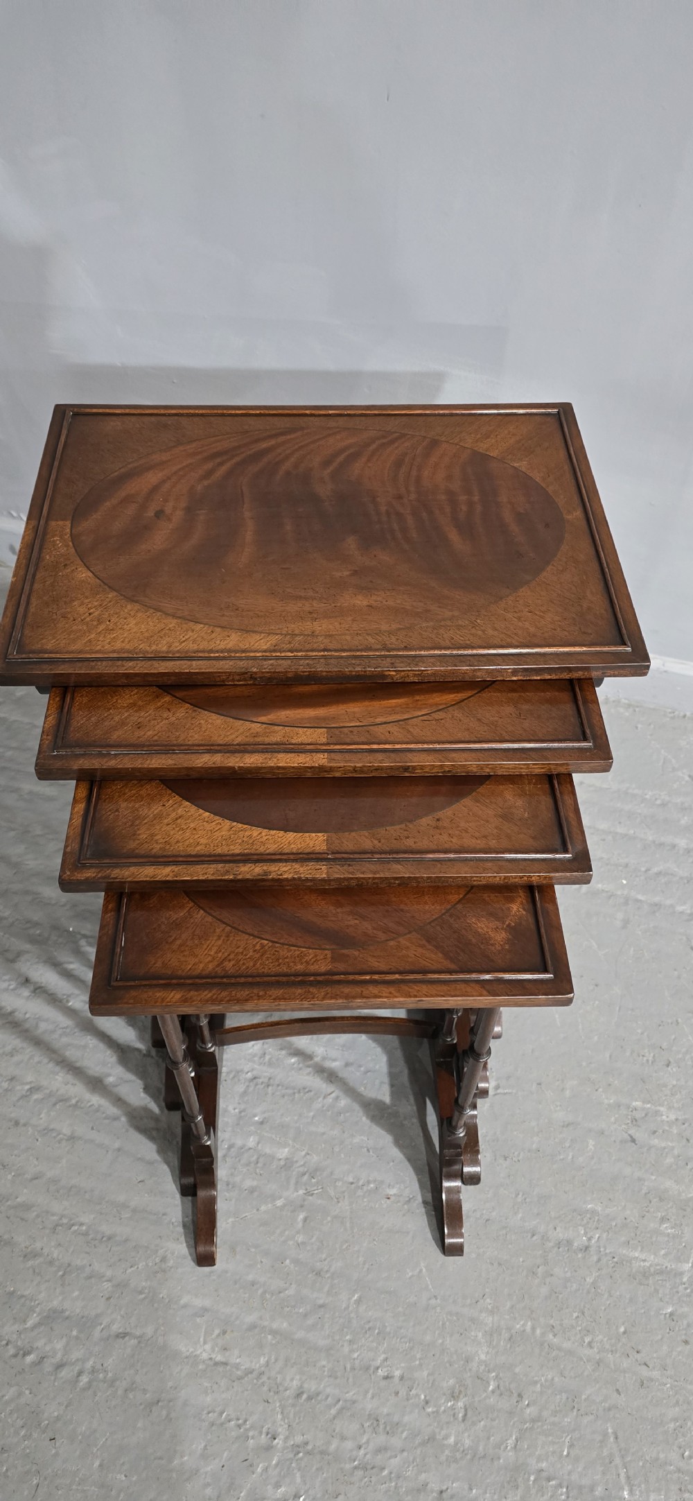 A set of four graduated mahogany quartetto tables featuring oval inlaid tops, ring-turned spindle legs, and curved stretchers. View VI