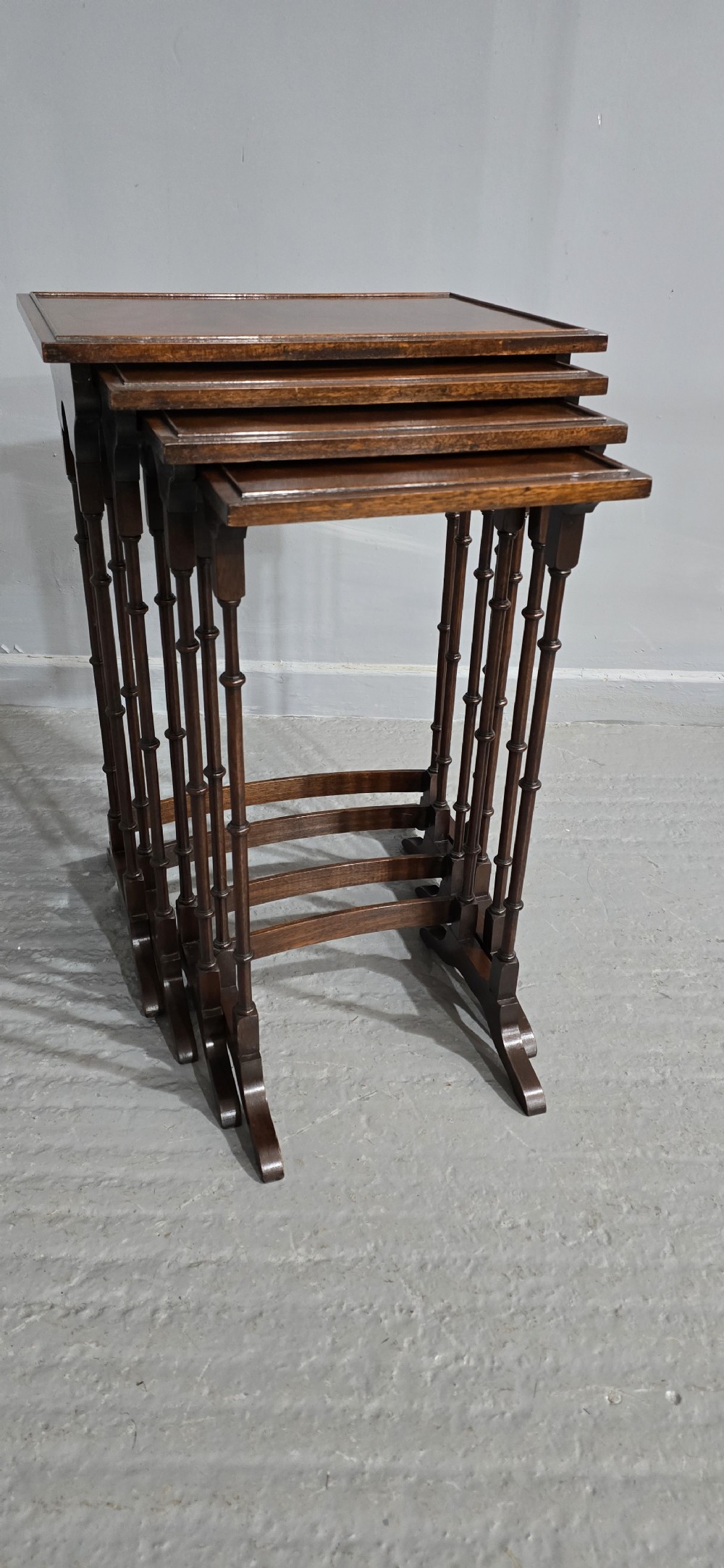 A set of four graduated mahogany quartetto tables featuring oval inlaid tops, ring-turned spindle legs, and curved stretchers. View IX