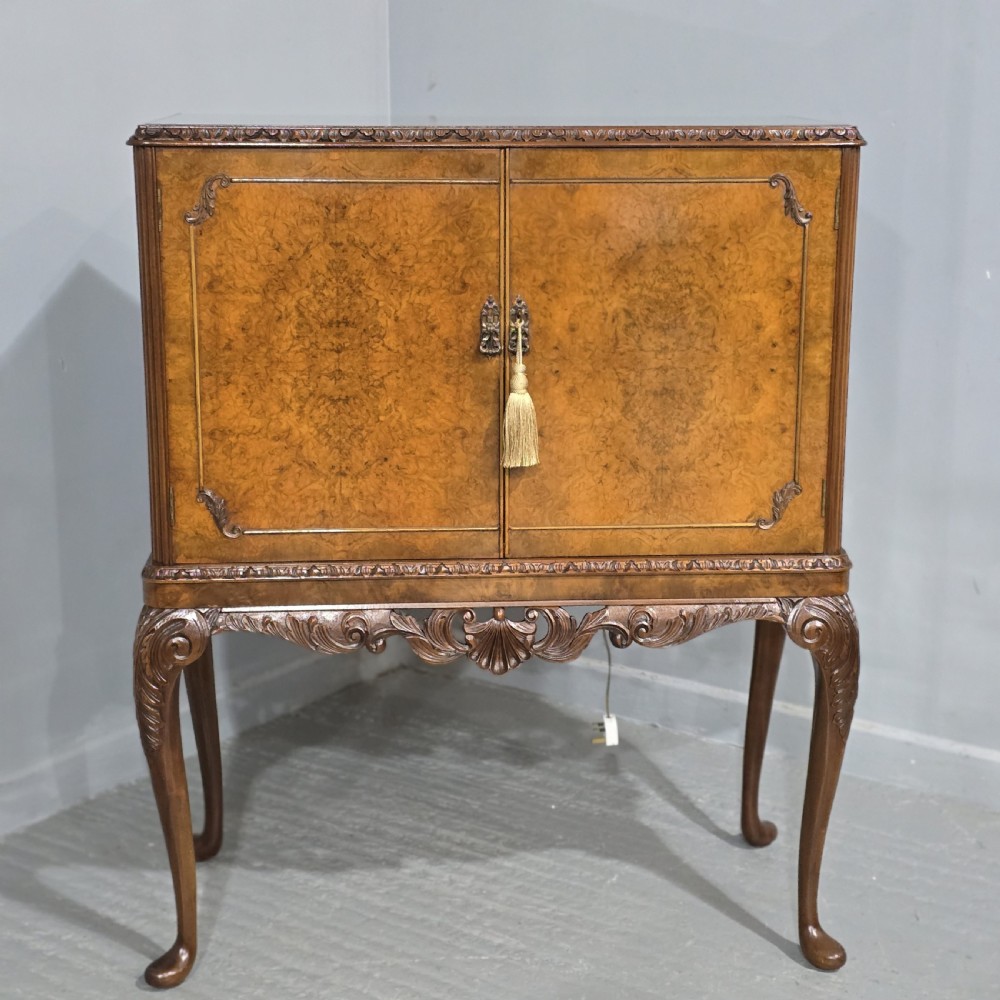 A freestanding burr walnut cocktail cabinet with double doors, carved shell apron, and cabriole legs.