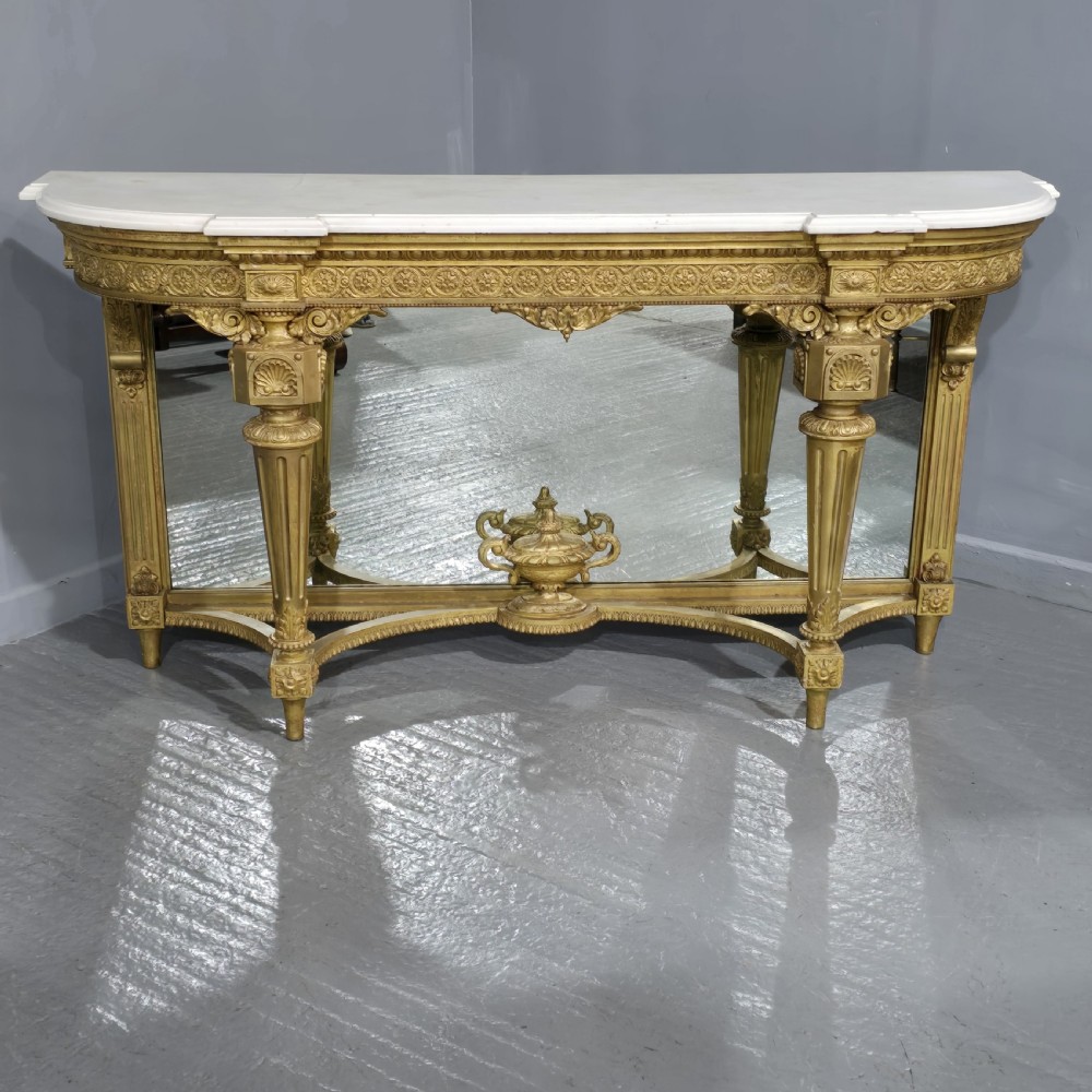A Victorian giltwood console table featuring a white marble top, mirrored back panel, fluted tapered legs, and a carved rosette frieze.