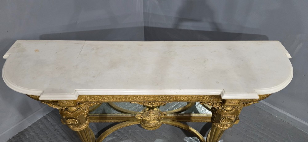 A Victorian giltwood console table featuring a white marble top, mirrored back panel, fluted tapered legs, and a carved rosette frieze. View III