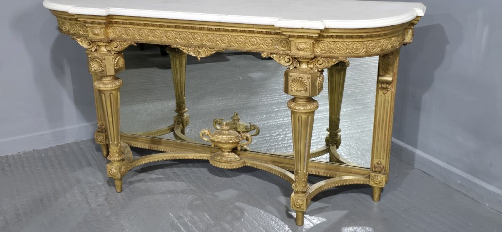 A Victorian giltwood console table featuring a white marble top, mirrored back panel, fluted tapered legs, and a carved rosette frieze. View V