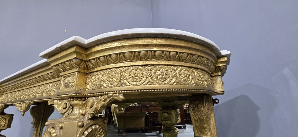 A Victorian giltwood console table featuring a white marble top, mirrored back panel, fluted tapered legs, and a carved rosette frieze. View XV