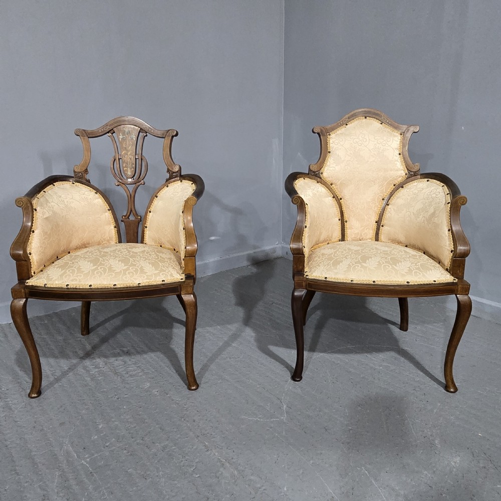 A pair of Edwardian Art Nouveau mahogany armchairs featuring cream floral upholstery, decorative back splats with marquetry inlay, and curved legs. View II