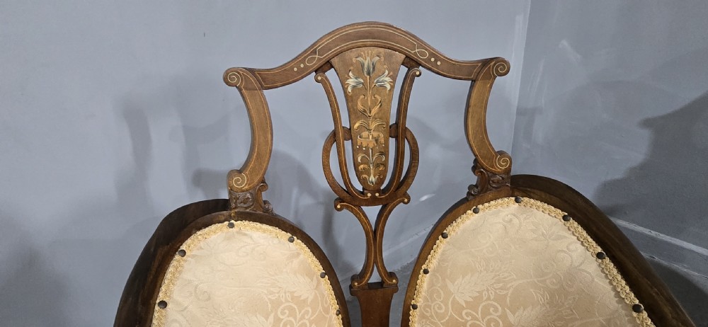 A pair of Edwardian Art Nouveau mahogany armchairs featuring cream floral upholstery, decorative back splats with marquetry inlay, and curved legs. View V
