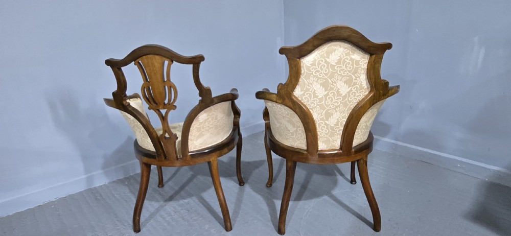 A pair of Edwardian Art Nouveau mahogany armchairs featuring cream floral upholstery, decorative back splats with marquetry inlay, and curved legs. View VII