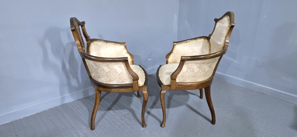 A pair of Edwardian Art Nouveau mahogany armchairs featuring cream floral upholstery, decorative back splats with marquetry inlay, and curved legs. View IX