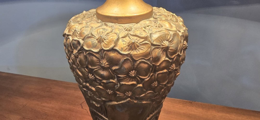 An Art Nouveau table lamp featuring a domed amber and red slag glass shade with decorative metal filigree set on a cast bronze floral base. View XIV