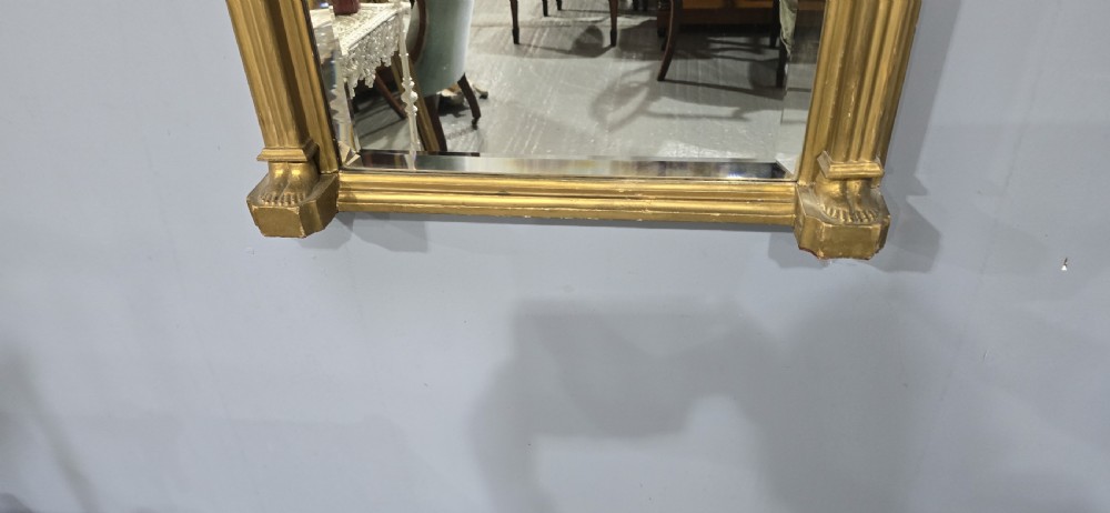 An antique gilded Regency wall mirror featuring an upper bas-relief frieze panel depicting a pastoral scene, fluted pilasters, and ball ornamentation along the upper cornice. View IV