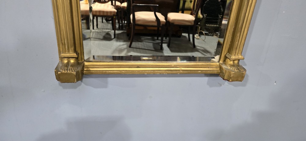 An antique gilded Regency wall mirror featuring an upper bas-relief frieze panel depicting a pastoral scene, fluted pilasters, and ball ornamentation along the upper cornice. View V