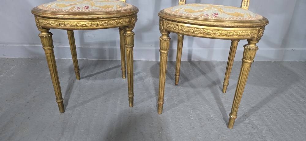 A pair of gold giltwood Louis XVI style side chairs featuring oval cane backs, carved splats, fluted legs, and patterned seat upholstery. View III