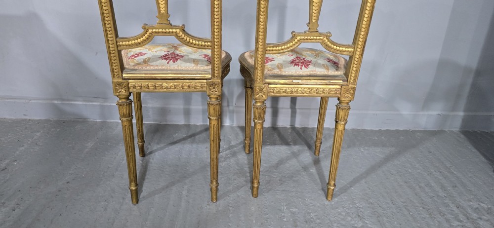 A pair of gold giltwood Louis XVI style side chairs featuring oval cane backs, carved splats, fluted legs, and patterned seat upholstery. View VIII