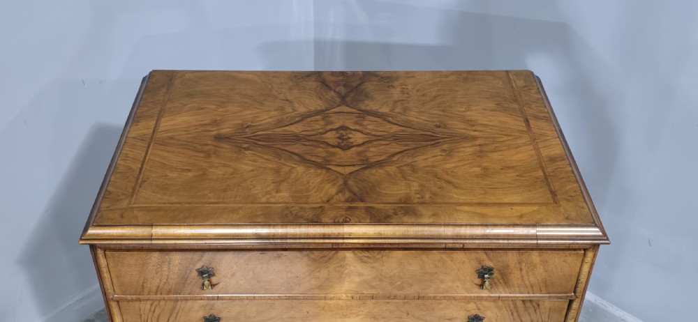 A tall antique burr walnut chest of drawers featuring six graduated drawers with brass drop handles and cabriole legs. View V
