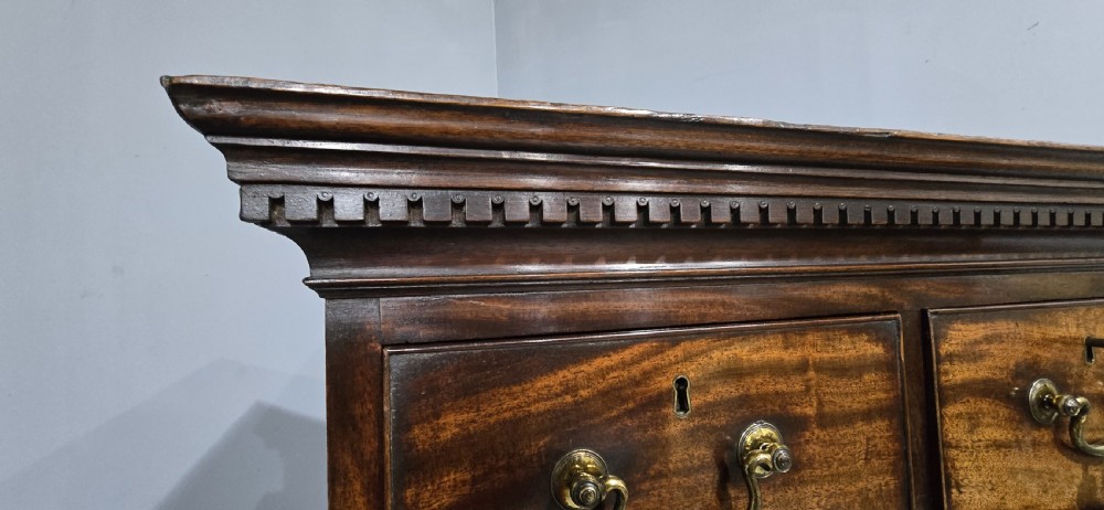 A tall Georgian mahogany chest on chest featuring two stacked drawer sections, flame mahogany grain, dentil cornice moulding, brass swan-neck handles, and bracket feet. View V