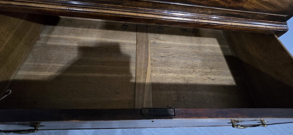 A tall Georgian mahogany chest on chest featuring two stacked drawer sections, flame mahogany grain, dentil cornice moulding, brass swan-neck handles, and bracket feet. View VII