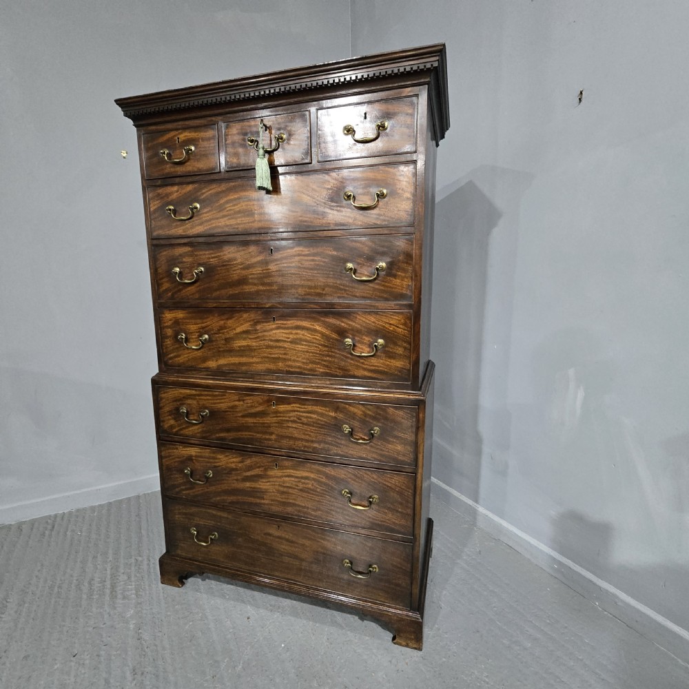 A tall Georgian mahogany chest on chest featuring two stacked drawer sections, flame mahogany grain, dentil cornice moulding, brass swan-neck handles, and bracket feet. View XIII