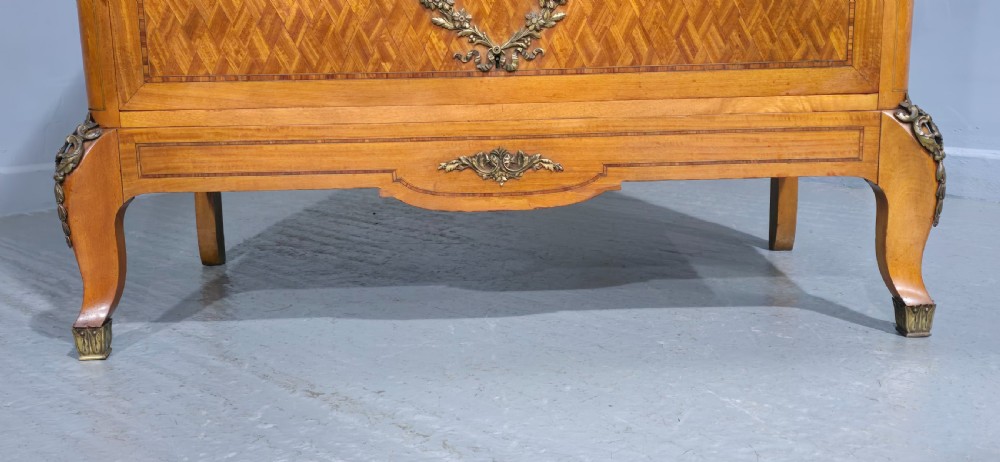 A French satinwood commode chest featuring herringbone parquetry veneer, a variegated marble top, and decorative gilt-bronze mounts. View VII