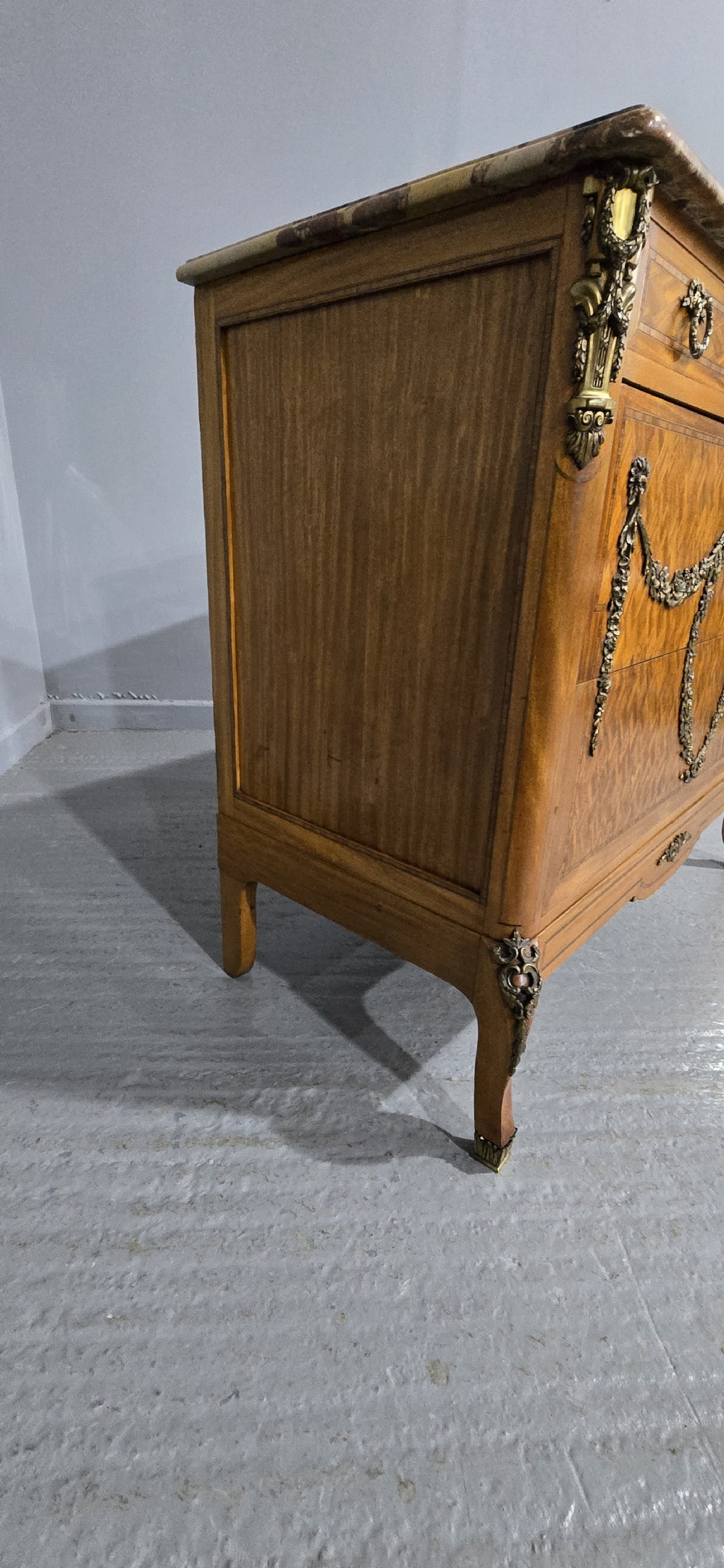 A French satinwood commode chest featuring herringbone parquetry veneer, a variegated marble top, and decorative gilt-bronze mounts. View VIII