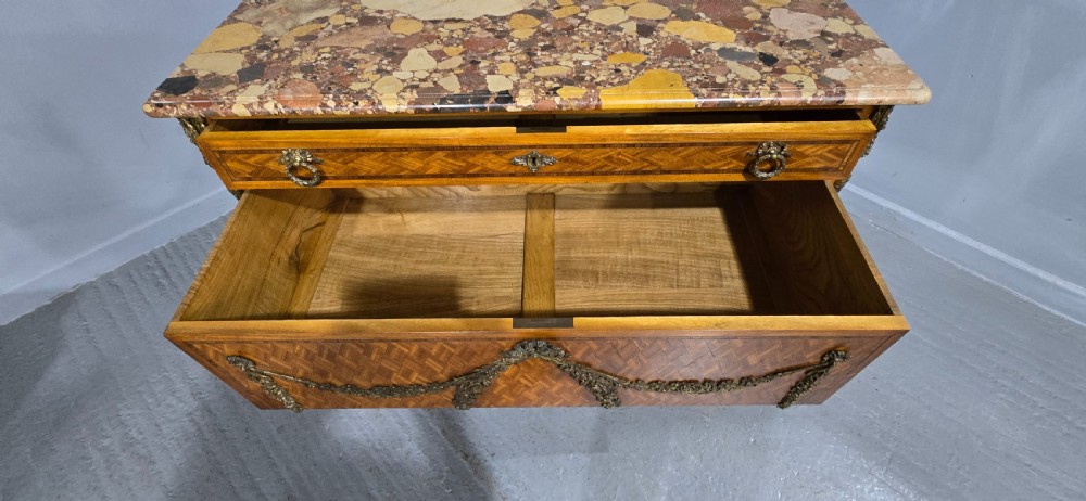 A French satinwood commode chest featuring herringbone parquetry veneer, a variegated marble top, and decorative gilt-bronze mounts. View XI
