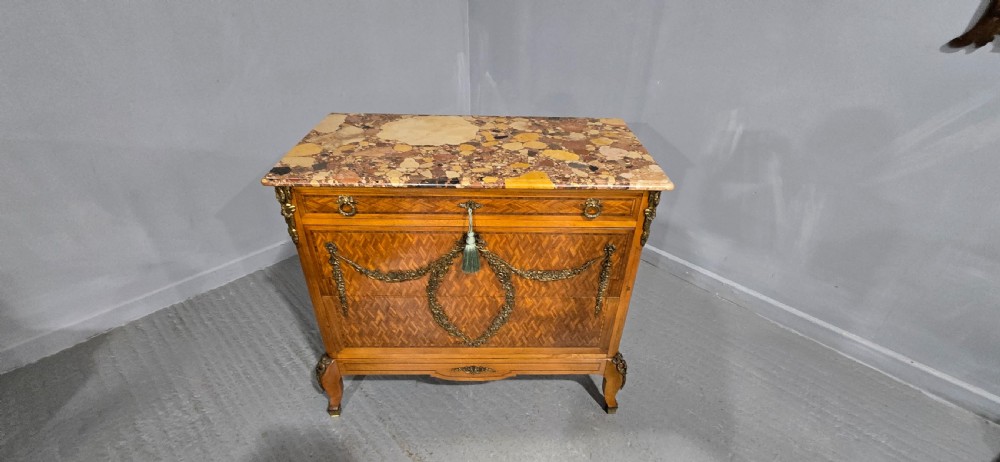 A French satinwood commode chest featuring herringbone parquetry veneer, a variegated marble top, and decorative gilt-bronze mounts. View XVIII