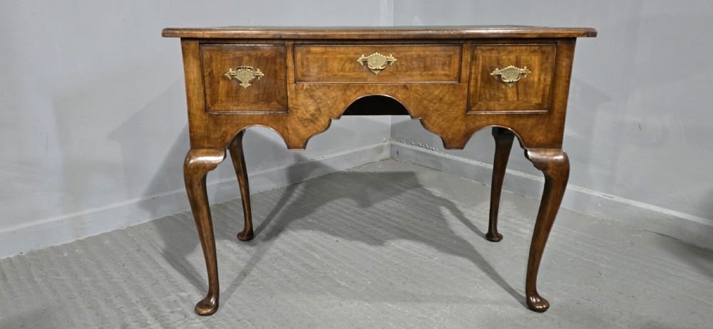 An antique Queen Anne style burr walnut lowboy featuring three drawers, an inset green leather writing top, brass handles, and slender cabriole legs. View II
