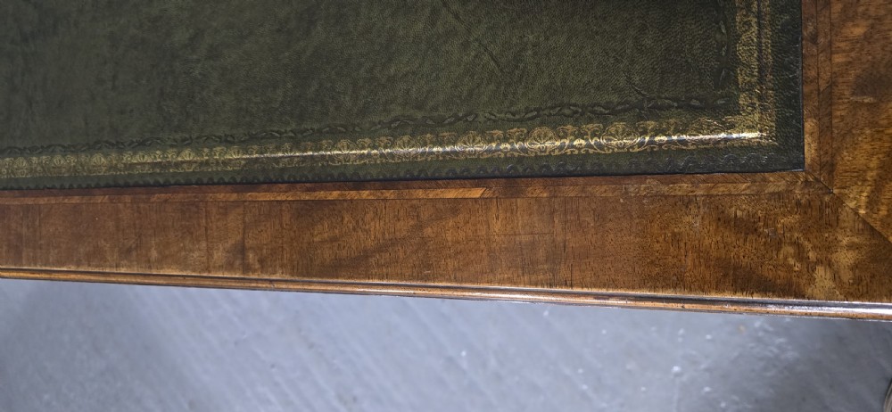 An antique Queen Anne style burr walnut lowboy featuring three drawers, an inset green leather writing top, brass handles, and slender cabriole legs. View XII